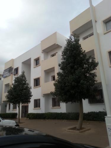 a white building with two trees in front of it at Entire Apartment in Agadir