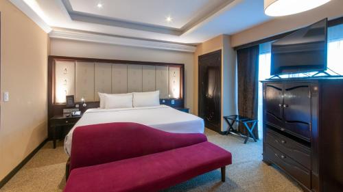 a bedroom with a large bed and a red bench at BelAir Unique a Wyndham Hotel in Mexico City