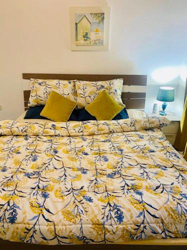 a bed with a yellow and blue comforter on it at Marjan Island Beach Apartment in Ras al Khaimah