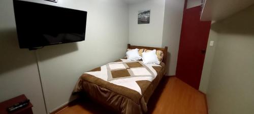 a small bedroom with a bed and a flat screen tv at Departamento Jesus Maria in Lima