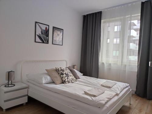 a white bed in a bedroom with a window at Lux Apartment close to Medicover and Paley in Warsaw