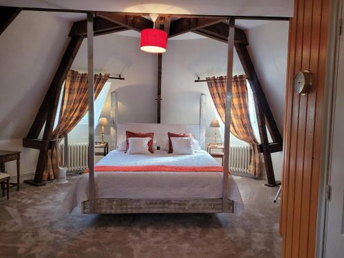 1 dormitorio con cama con dosel y almohadas rojas en La Coulee Verte en Saint-Aubin-de-Luigné