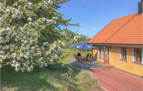 a house with a deck with a table and an umbrella at 3 Bedroom Lovely Home In Adelsö in Adelsö