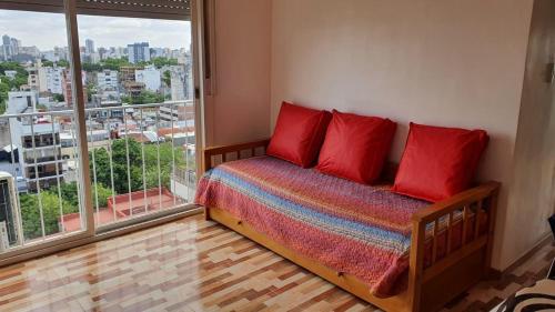 Un dormitorio con una cama con almohadas rojas y una gran ventana. en Hermoso 2 ambientes en Palermo Hollywood en Buenos Aires