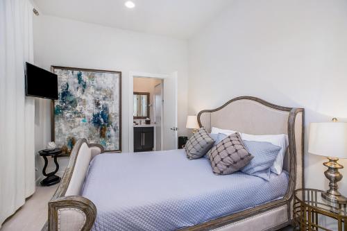 a white bedroom with a bed with blue sheets and pillows at Skyline Loft in Houston