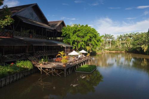 ein Gebäude mit Tischen und Stühlen auf einem Fluss in der Unterkunft Sepilok Nature Lodge - Formerly known as Sepilok Nature Resort in Sandakan