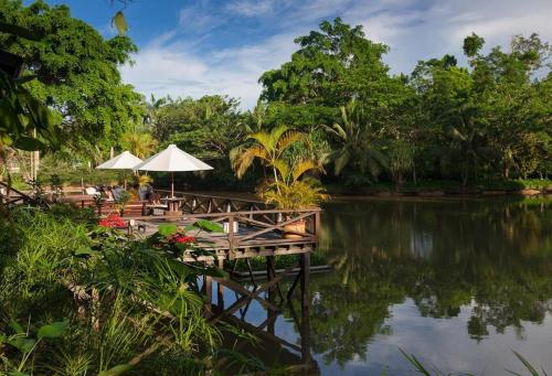 un molo con tavoli e ombrelloni su un lago di Sepilok Nature Lodge - Formerly known as Sepilok Nature Resort a Sandakan