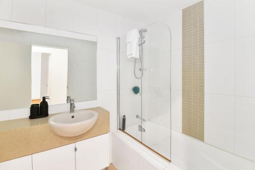 a white bathroom with a sink and a shower at Coast Apartments 7 in The Entrance