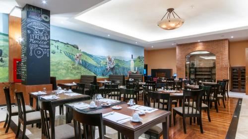 a dining room with tables and chairs and a mural at BelAir Unique a Wyndham Hotel in Mexico City