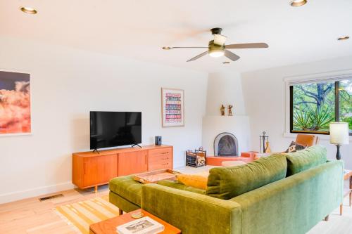 a living room with a green couch and a tv at Casita Colibri in Santa Fe