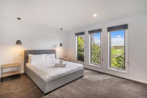 a bedroom with a bed and large windows at Central Park in Port Fairy