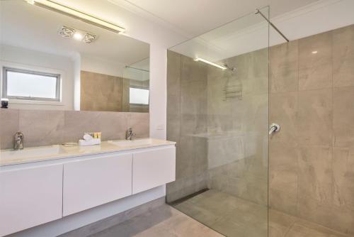 uma casa de banho com uma cabina de duche em vidro e um lavatório. em Central Park em Port Fairy