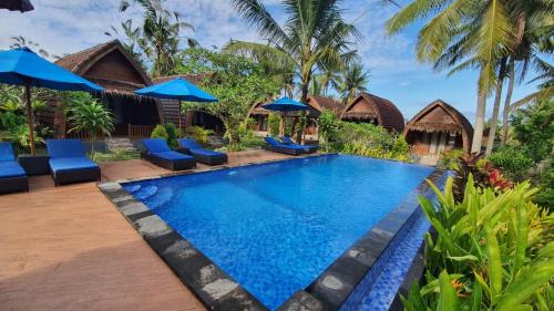 a pool at a resort with blue chairs and umbrellas at Kelingking Tatakan Bungalow in Nusa Penida