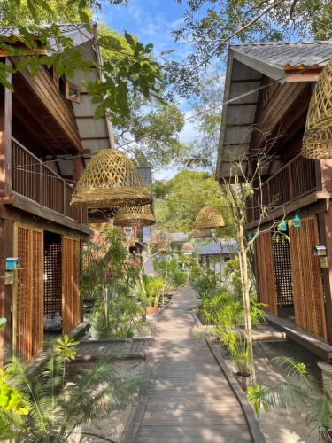 um caminho entre dois edifícios com árvores em The Temak Villa em Pantai Cenang