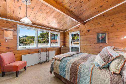 una camera da letto con pareti in legno, un letto e una sedia di Barne the Bentley - Taupo Holiday Home a Taupo