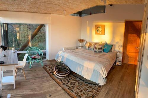 a bedroom with a bed and a table and a window at Espectacular Loft en Zapallar in Zapallar