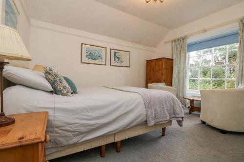1 dormitorio con cama, ventana y silla en Eden House Wing, en Saint Keverne