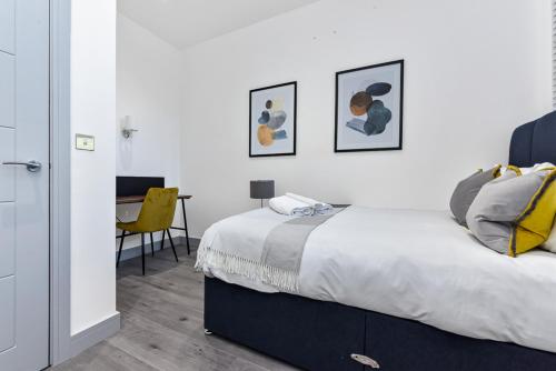 倫敦的住宿－Lovely 2 Bedroom Apartment in Greater London，一间卧室配有一张床和一张带黄椅的桌子
