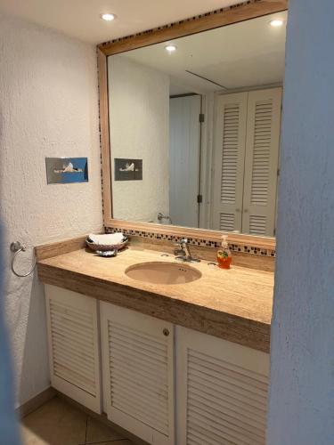 baño con lavabo y espejo grande en Hermoso Depto con vista al mar en zona hotelera., en Cancún
