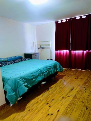 a bedroom with a green bed and red curtains at Departamento 1 ambientes amueblado rafael calzada zona sur in Rafael Calzada
