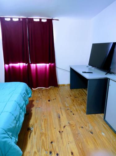 Schlafzimmer mit einem Bett und einem Schreibtisch mit einem Computer in der Unterkunft Departamento 1 ambientes amueblado rafael calzada zona sur in Rafael Calzada