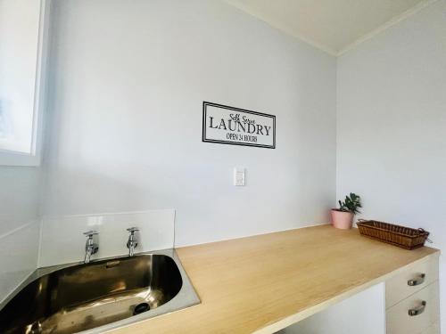 a kitchen with a sink and a sign on the wall at LA SOL 1 - All you need for a stay, close to Uni, town & Cambridge in Hamilton