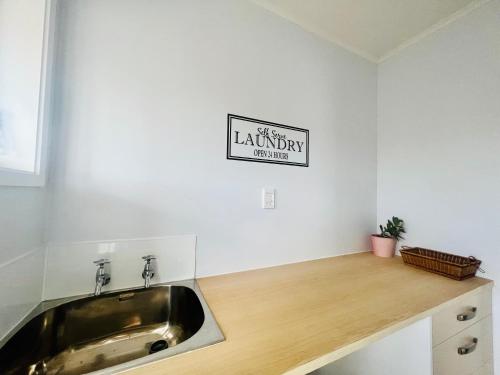 a kitchen with a sink and a sign on the wall at La Sol - All you need for a stay, close to town, University & Cambridge in Hamilton