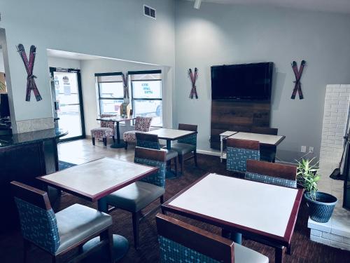 Quality Inn Durango في دورانجو: مطعم بطاولات وكراسي وتلفزيون بشاشة مسطحة