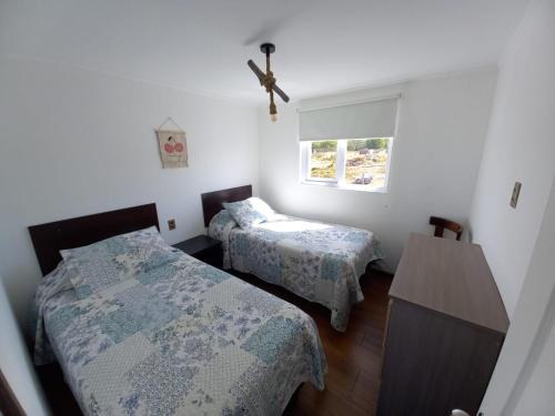 1 dormitorio con 2 camas y ventana en Cabañas Altos de Leñadura, en Punta Arenas