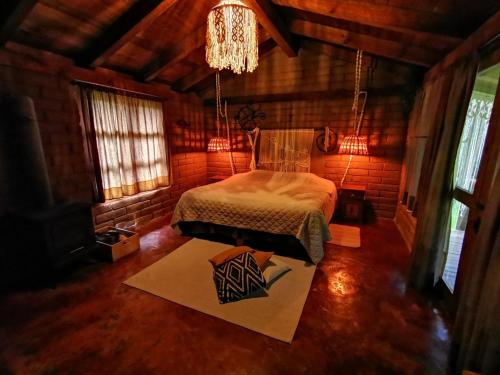 a bedroom with a bed in a room with a chandelier at Luchita Mia Eco Cabañas Boutique in Zacatlán