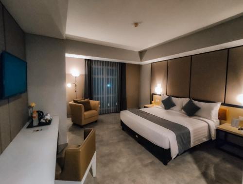 a hotel room with a large bed and a chair at BeSS Mansion Hotel Surabaya in Wonocolo