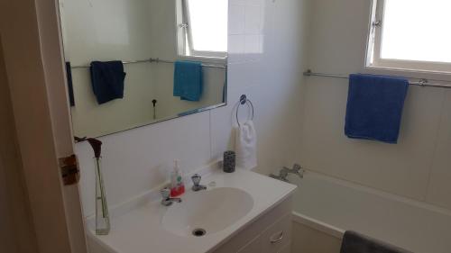 ein weißes Badezimmer mit einem Waschbecken und einem Spiegel in der Unterkunft Quiet cul de sac, close to Abel Tasman in Motueka
