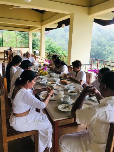 a group of people sitting at a table eating food at Nature Walk Resort in Kandy