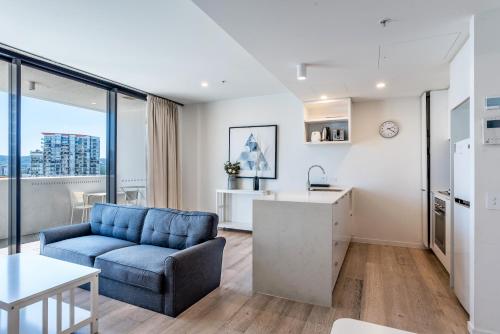 a living room with a blue couch and a kitchen at Serain Residences On Merivale Street in Brisbane