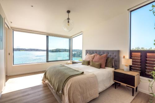 a bedroom with a large bed and large windows at Moana Retreat in Putaki Bay