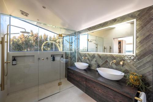 a bathroom with two sinks and a glass shower at Moana Retreat in Putaki Bay