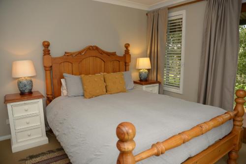 a bedroom with a wooden bed with two night stands and two lamps at Borrodell Vineyard in Orange