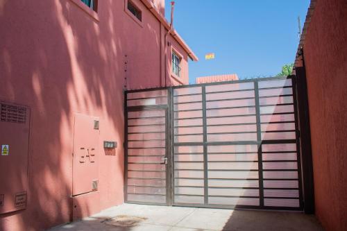 une grande porte métallique devant un bâtiment rouge dans l'établissement Aladdín Departamentos, à Luján de Cuyo