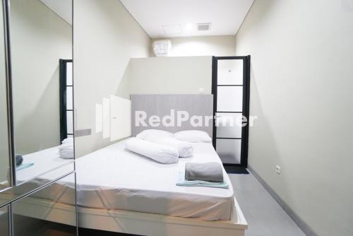 Habitación con cama con sábanas y almohadas blancas. en Tomang Gelong Guest House Syariah Mitra RedDoorz, en Yakarta