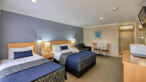 a hotel room with two beds and a desk at Edward Parry Motel and Apartments in Tamworth