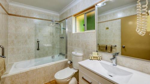 a bathroom with a sink and a tub and a toilet at Edward Parry Motel and Apartments in Tamworth