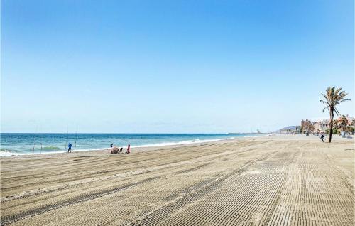 a beach with people and a palm tree and the ocean at 2 Bedroom Amazing Apartment In Casares in Casares