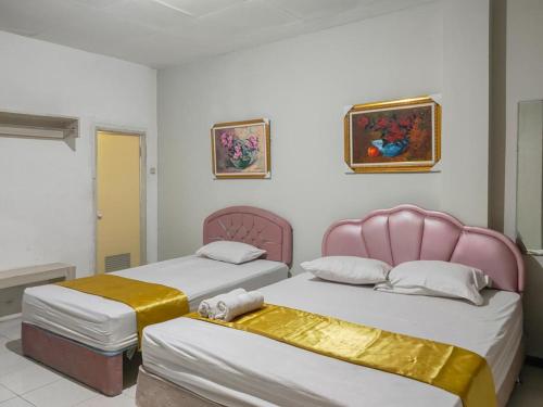 two beds sitting next to each other in a room at Yellow Sapphire RedPartner near Mayjend Sungkono in Surabaya