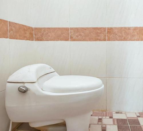 a white toilet in a bathroom with a tiled wall at Yellow Sapphire RedPartner near Mayjend Sungkono in Surabaya