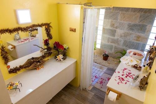 La salle de bains est pourvue de murs jaunes, d'un lavabo et d'un miroir. dans l'établissement Fare Manava, à Bora Bora