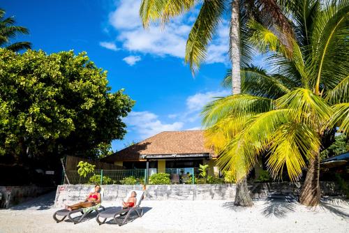 two people are sitting on chairs on the beach at Fare Manava in Bora Bora