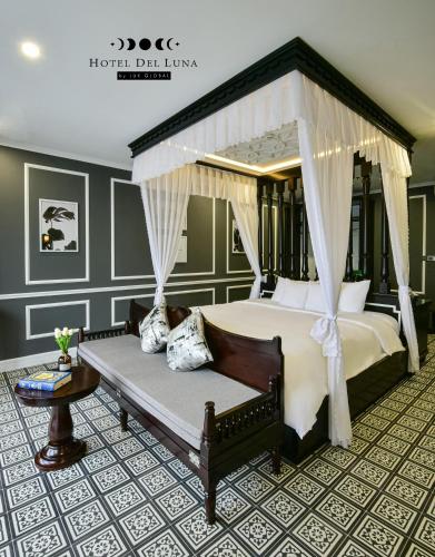 a bedroom with a canopy bed and a couch at Hotel Del Luna Boutique in Da Nang