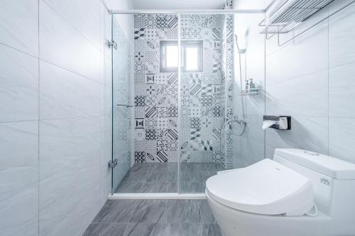 a white bathroom with a toilet and a shower at Choco Style Inn in Taitung City