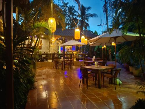 a patio with tables and chairs and umbrellas at night at Shanti Boutique Hotel in Srithanu
