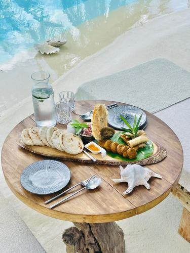 a table with a plate of food on a table by the water at The Beach House Ocam Ocam in Busuanga